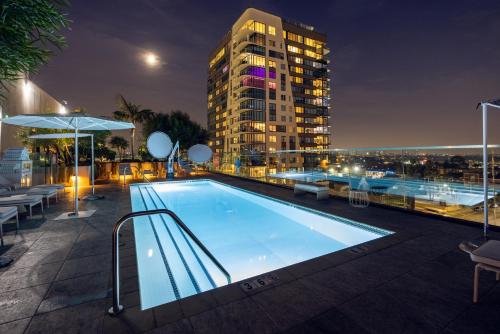 a swimming pool on the roof of a building at night at The Godfrey Hotel Hollywood in Los Angeles