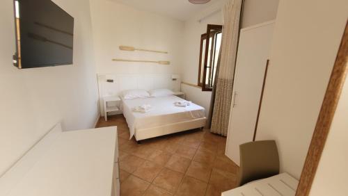 a small white bedroom with a bed and a chair at Le Camere Del Giardino in San Vito lo Capo