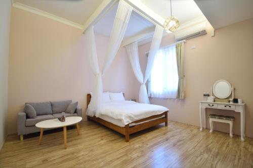 台东开封小栈民宿-二馆的一间卧室，里面有一张床、一张沙发和一张桌子