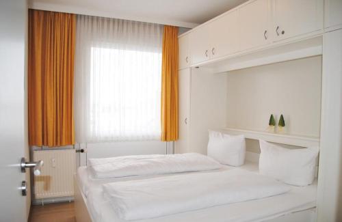 um quarto branco com uma cama e uma janela em Iderhoff Iderhoff 19 em Norderney