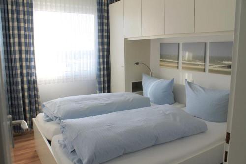a bedroom with two beds with blue sheets and a window at Iderhoff Iderhoff 08 in Norderney