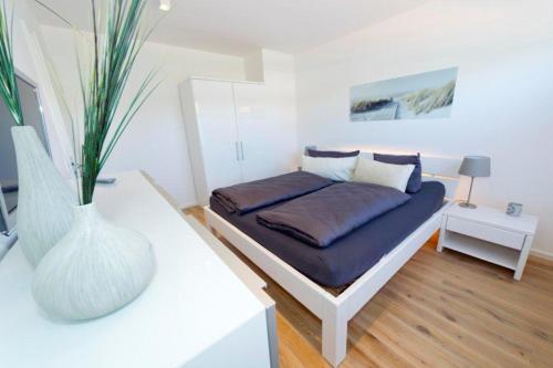 a bedroom with a bed and a vase on a table at Traum vom Meer Traum vom Meer 2 in Norderney