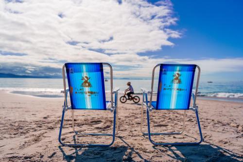 2 sillas de playa sentadas en la arena de la playa en HANNA Flat Amsterdam en Florianópolis