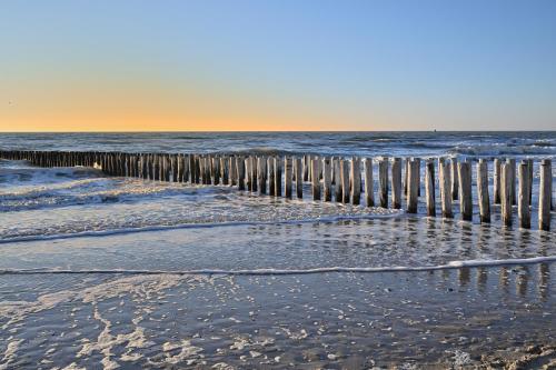 a wooden fence on the beach near the ocean at Unieke stadswoning met jacuzzi en sauna max 8 pers in Goes