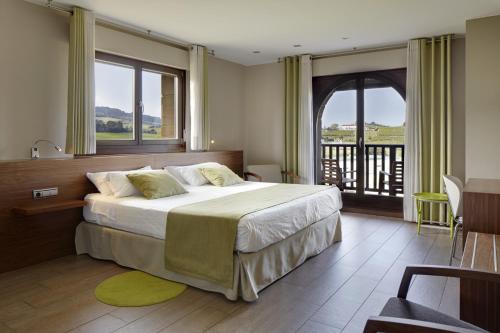 a bedroom with a large bed and a balcony at Hotel Rural Gaintza in Getaria