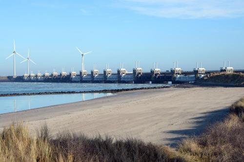 a beach with a pier and windmills in the background at Unieke stadswoning met jacuzzi en sauna max 8 pers in Goes