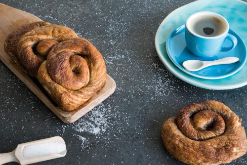 a table with a plate of cinnamon rolls and a cup of coffee at Unieke stadswoning met jacuzzi en sauna max 8 pers in Goes