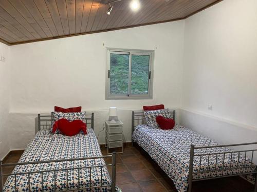 two beds in a room with a window at Casa Rural La Yedra San Mateo in Arbejales
