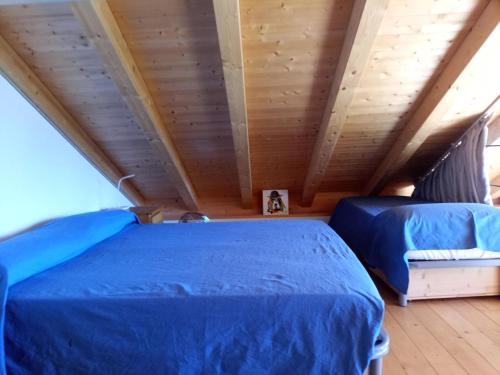Duas camas num quarto com tecto em madeira em casa vacanze Ca'del Miro Montemezzo em Bugiallo