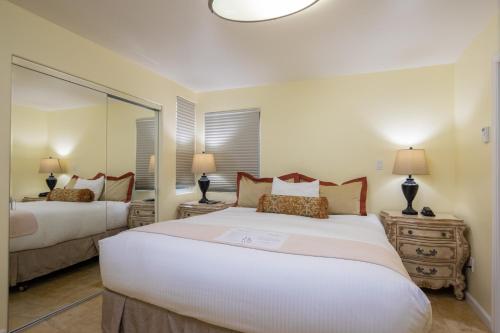 a bedroom with two beds and a large mirror at The Vendange Carmel Inn & Suites in Carmel
