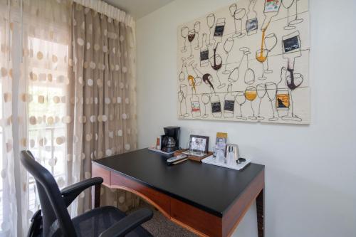 a desk in a room with a picture of glasses on the wall at The Vendange Carmel Inn & Suites in Carmel