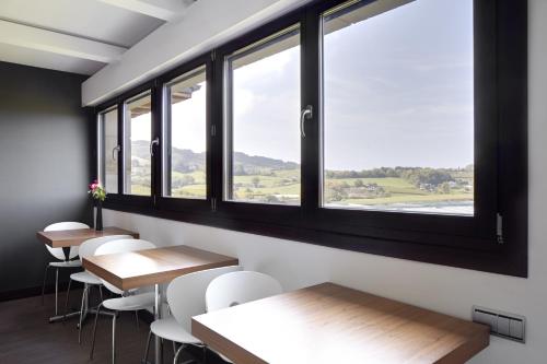 a row of tables and chairs in a room with windows at Hotel Rural Gaintza in Getaria