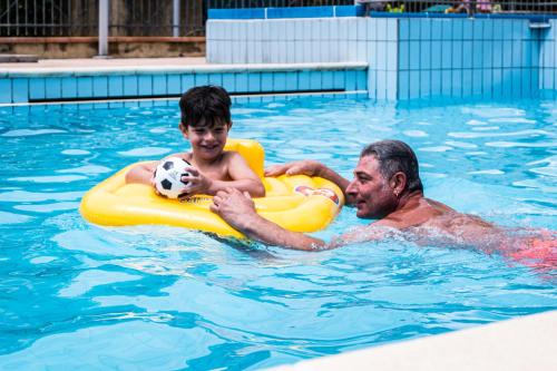 dos hombres en la piscina con una pelota de fútbol en Residence Le Saline, en Borgio Verezzi