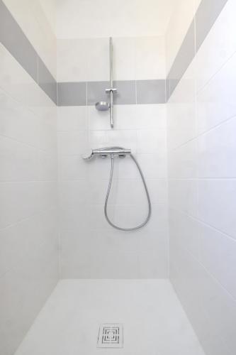 La salle de bains blanche est pourvue d'une douche avec un tuyau. dans l'établissement LE COOL LEVEL, à Chalon-sur-Saône