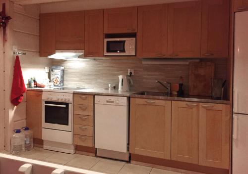 una cocina con armarios de madera y electrodomésticos blancos en Holiday Cabin Kerimaa 90, en Kerimäki