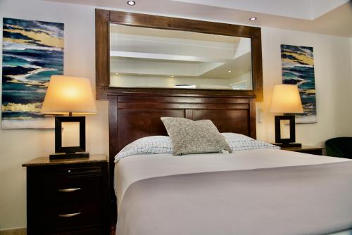 a bedroom with a bed with two lamps and a mirror at Rio Suites in Tijuana