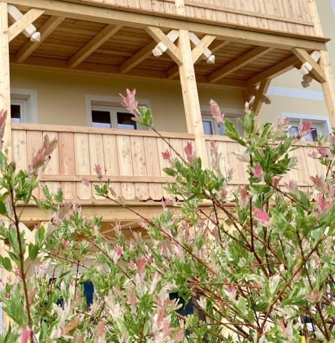 a wooden house with a wooden deck with pink flowers at Heissgut in Altenmarkt im Pongau