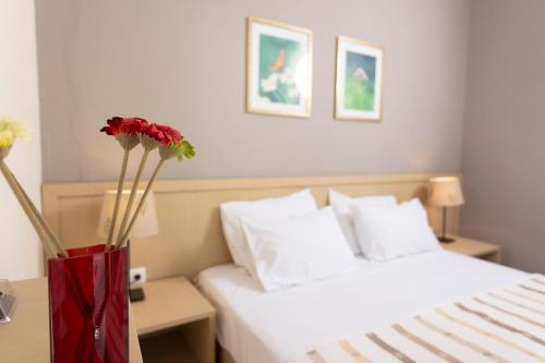 a red vase with flowers in front of a bed at MaGia Peristeridi in Polychrono