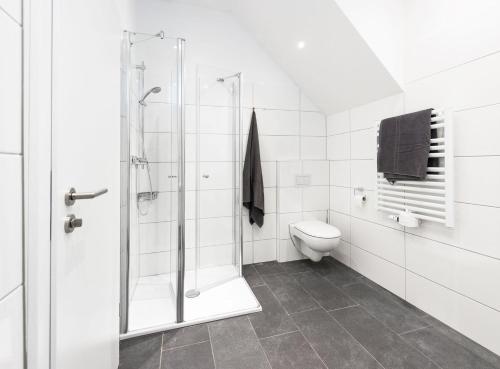 a white bathroom with a shower and a toilet at Lüttje Hütt Mien Lüttje Hütt 01 in Norderney