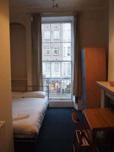 a room with two beds and a large window at Paddington Flats in London