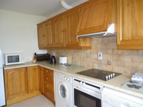 a kitchen with wooden cabinets and a washing machine at Portmagee Seaside Cottages in Portmagee