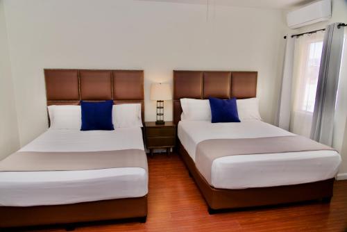 two beds in a hotel room with blue pillows at Rio Suites in Tijuana