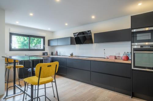 une cuisine avec des armoires noires et une chaise jaune dans l'établissement Baleni House, à Amboise