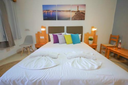 a bedroom with a large white bed with colorful pillows at Malia Boutique Studios in Malia