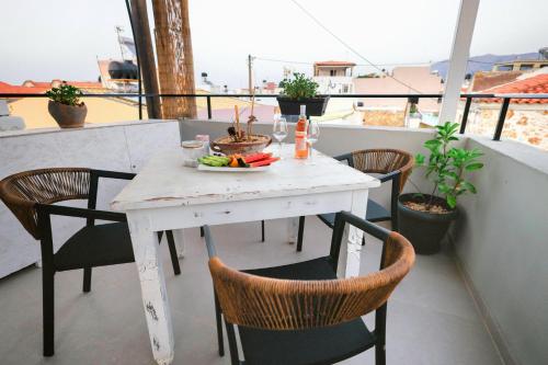 a white table with chairs and a bowl of fruit on a balcony at Malia Boutique Studios in Malia