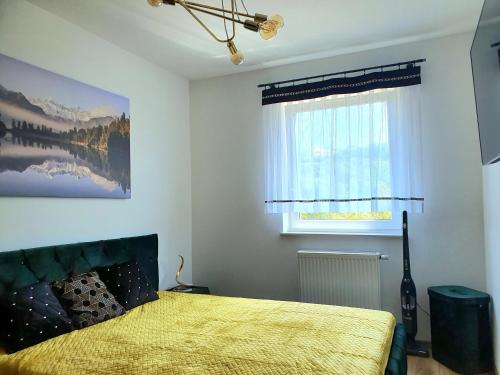 een slaapkamer met een bed met een gele sprei en een raam bij Apartamenty Ski & Fun Spokojna in Wisła