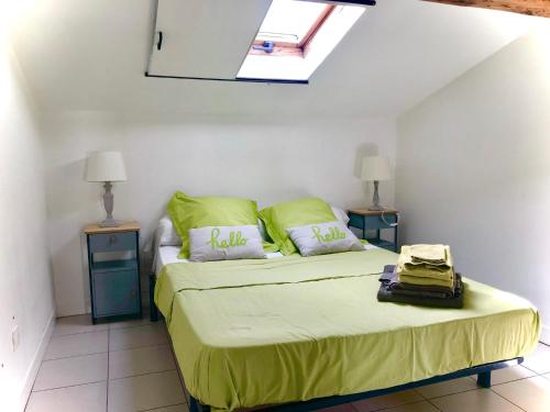une chambre avec un lit avec des draps verts et une lucarne dans l'établissement Les couleurs de Balaruc Les Bains, à Balaruc-les-Bains