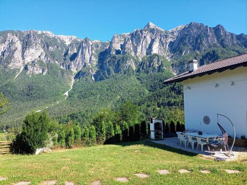 a house with a picnic table and mountains in the background at Chalet cima 12 Valle di Sella in Borgo