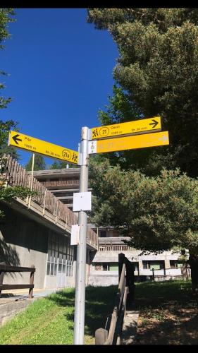 a pole with yellow street signs in front of a building at Le joli coin in Pila