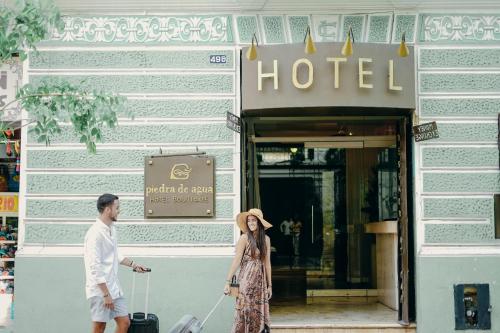 a man and a woman pulling a suitcase outside a hotel at Piedra de Agua Merida in Mérida