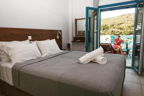 un dormitorio con una cama y una mujer sentada en un balcón en HELIADES SUITES, en Panteli