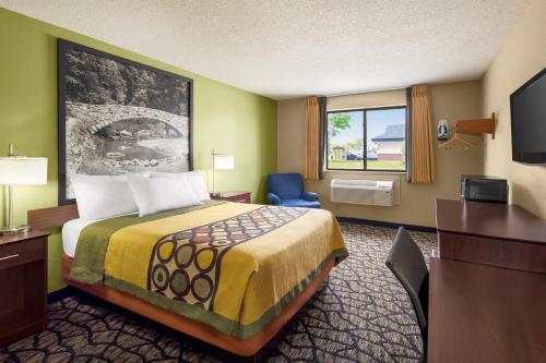 a hotel room with a bed and a desk and a television at Super 8 by Wyndham Ankeny/Des Moines Area in Ankeny