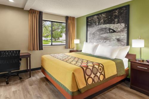 a hotel room with a bed and a desk and a window at Super 8 by Wyndham Ankeny/Des Moines Area in Ankeny