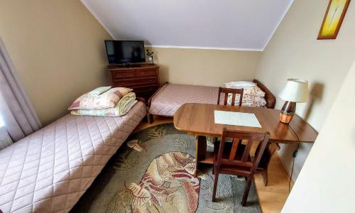a small room with a table and a bed and a desk at Agroturystyka Pokoje U Sołtysa in Goniadz