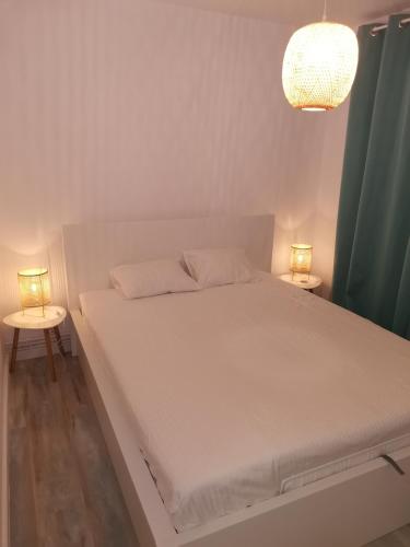 a white bed with two lamps on two tables at Bloom Box Apartments in Craiova