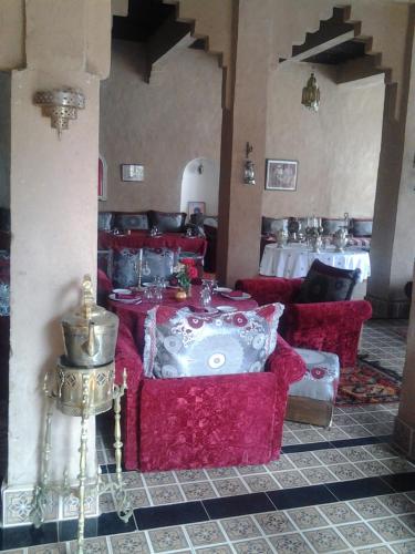 a room with red couches and tables in a building at Kasbah Itrane in Tamnougalt