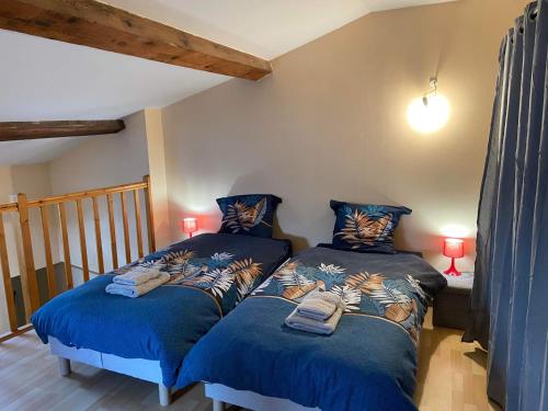 2 Betten in einem Zimmer mit blauen Decken und Lampen in der Unterkunft La maison bleue in Lautrec