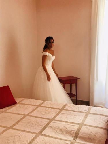 a woman in a wedding dress standing in a bedroom at Gualtiero Camere & Suite in Caltagirone