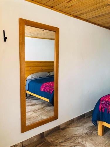 a mirror in front of a bed in a room at Hotel María del Tío Molcas in Creel