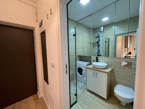 uma casa de banho com um lavatório e uma máquina de lavar roupa em Riverside Luxury Apartment Near President Palace em Bucareste