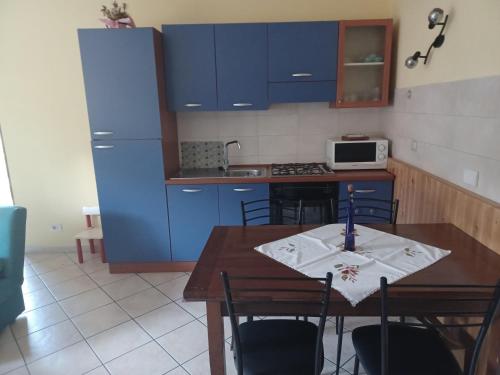 a kitchen with a wooden table and blue cabinets at la Cambuse in Torre Pellice