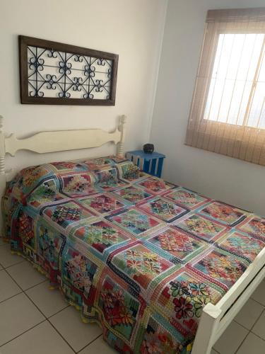 uma cama com uma colcha colorida num quarto em Casa beira mar Jacaraipe. em Serra