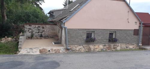a white house with a stone wall and windows at Apartmán Levandule in Lesŭňky