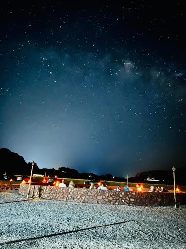 a starry night with a stone wall and the sky at Shakria Bedouin Life Camp in Wadi Rum