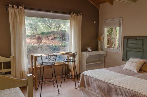 Un dormitorio con una cama y un escritorio y una ventana. en Entre Sierras B&B, en Tandil