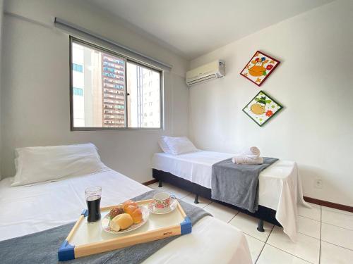 a hotel room with two beds and a tray of fruit at CB54 - Currasqueira, 2 Dorm Climatizados, Garagem in Balneário Camboriú